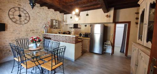 une cuisine avec une table, des chaises et un réfrigérateur dans l'établissement Le Mas de Doat, Gîte de Charme 4 étoiles dans le Triangle d Or proche Gaillac et Albi, à Senouillac
