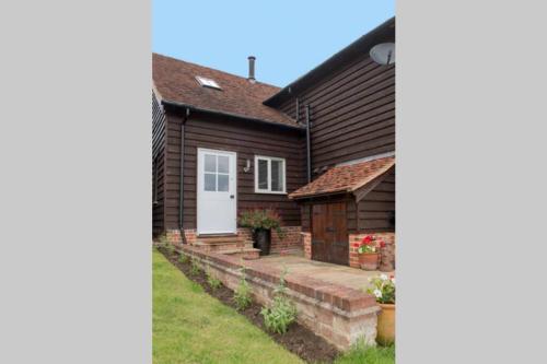 a house with a white door and a yard at Immaculate barn annexe close to Stansted Airport in Great Dunmow