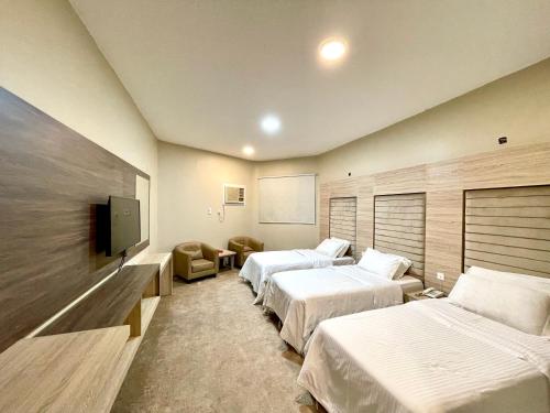 a hotel room with two beds and a flat screen tv at Relax Day Hotel in Tabuk