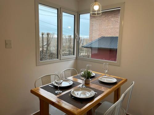 a dining room with a table with chairs and windows at South Apartments in El Calafate