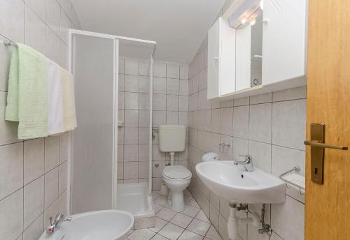 a white bathroom with a toilet and a sink at Apartments Villa Estella in Srima