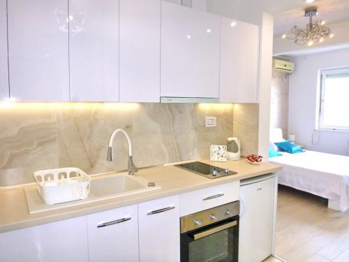 - une cuisine avec des placards blancs, un lavabo et un lit dans l'établissement Arena Dream Studio, à Belgrade