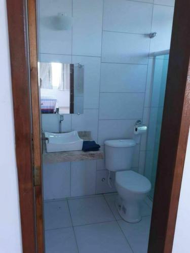 a white bathroom with a toilet and a sink at Recanto Concha Marinha in Prado