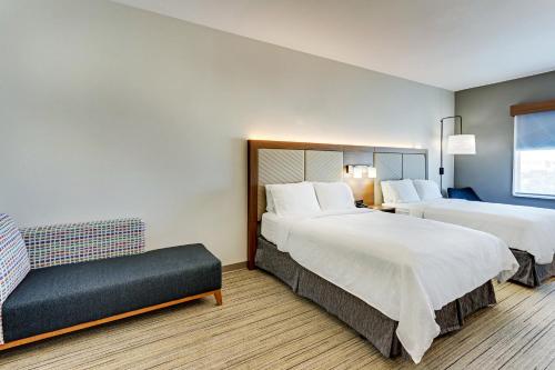 a hotel room with two beds and a chair at Holiday Inn Express Hotel and Suites Weatherford by IHG in Weatherford