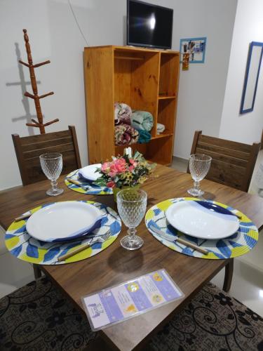 a wooden table with plates and glasses on it at Hospedagem Elite térreo in Cunha