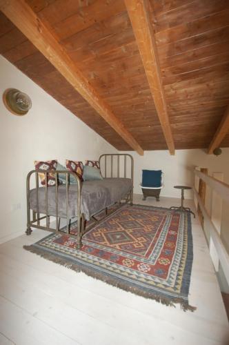 a bedroom with a bed with a rug and a wooden ceiling at L' Alcova Del Conte in Dragoni