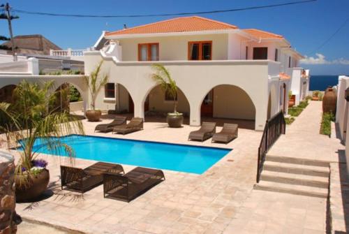 a villa with a swimming pool in front of a house at Pelagus Guest House in Hermanus
