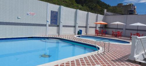 a swimming pool with chairs and umbrellas next to a building at Hotel Emperador in Barbosa