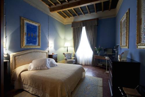 ピエトラサンタにあるResidenza Palazzo Visdominiの青い壁のベッドルーム1室、ベッド1台、デスクが備わります。