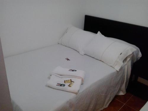 a white bed with two white towels on it at Hotel Casa Gabriela in Bogotá