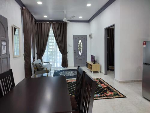 a living room with a dining room table and a kitchen at Kayangan Inn in Rantau Panjang
