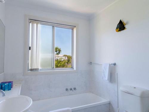 uma casa de banho com uma banheira, um lavatório e uma janela em Seachange Townhouse 4 em Hawks Nest