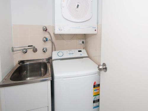 uma pequena cozinha com um lavatório e uma máquina de lavar roupa em Providence Apartment 3 em Hawks Nest