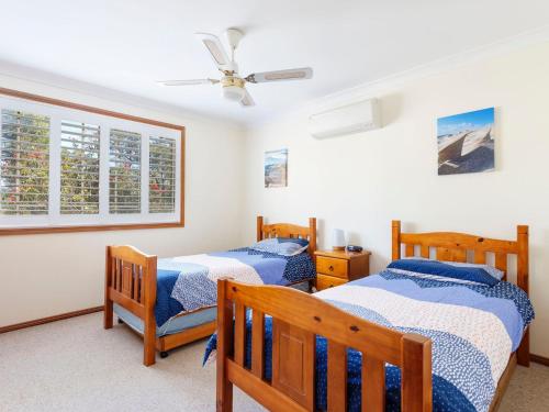 a bedroom with two beds and a ceiling fan at Jimmys Beach Escape in Hawks Nest