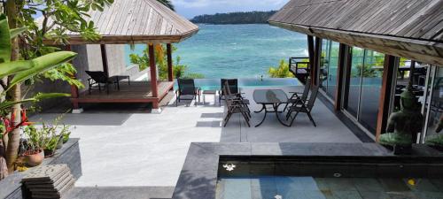 a patio with chairs and a swimming pool next to the ocean at Surin Beach Ocean front Villa between Kamala and BangTao Beaches in Surin Beach