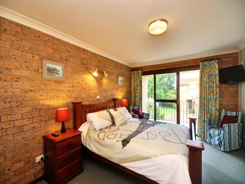 a bedroom with a bed and a brick wall at Close To The Main Surf Beach in Hawks Nest