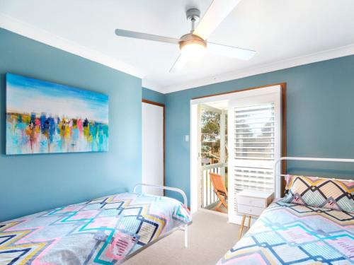 a blue bedroom with a bed and a ceiling fan at Tilly and Annies Place in Hawks Nest