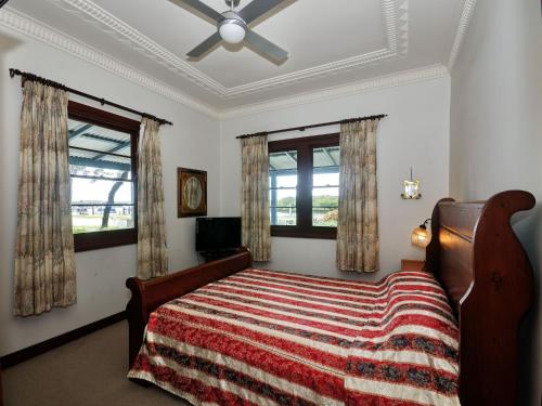 ein Schlafzimmer mit einem Bett und zwei Fenstern in der Unterkunft The Lakes Cottage in Tea Gardens