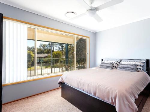 a bedroom with a bed and a large window at Close To The Myall River Pet Welcome in Hawks Nest