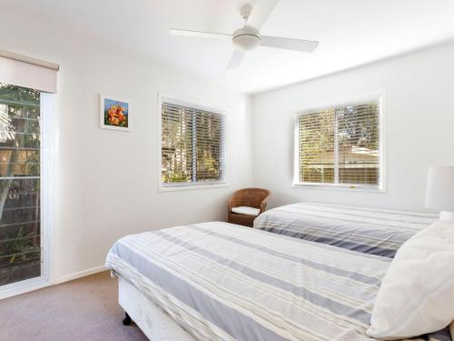 two beds in a bedroom with two windows at Gumbeachy Pet Friendly Free WiFi in Hawks Nest