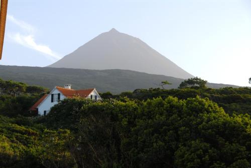 a house on a hill with a mountain in the background at Casa do Areal in São Roque do Pico