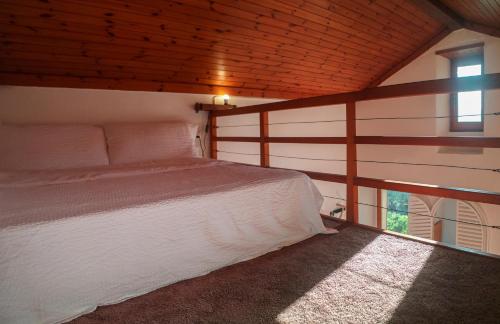 a bedroom with a white bed and a window at Wisteria House - Holiday Apartment in Cadenazzo