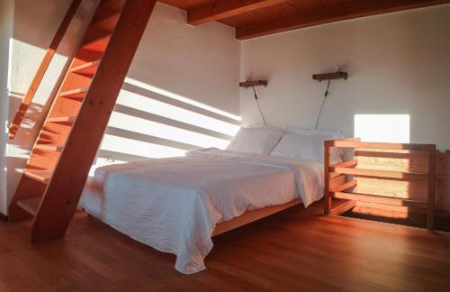 1 dormitorio con 1 cama en una habitación con suelo de madera en Wisteria House - Holiday Apartment, en Cadenazzo