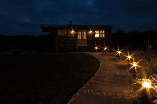 a log cabin at night with lights on the path at Daisy Park Shepherds Hut in Looe