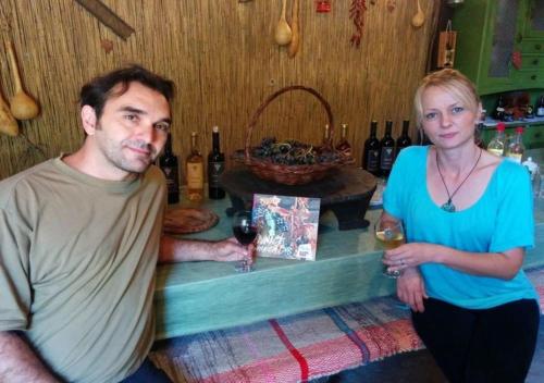 a man and a woman standing at a bar with a glass of wine at Rajacke pivnice Country House C`est La Vie in Rajac
