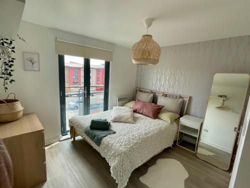 a bedroom with a bed and a large window at Family Friendly Maritime Apartment in Swansea