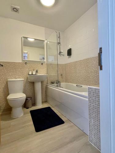 a bathroom with a tub and a toilet and a sink at Family Friendly Maritime Apartment in Swansea