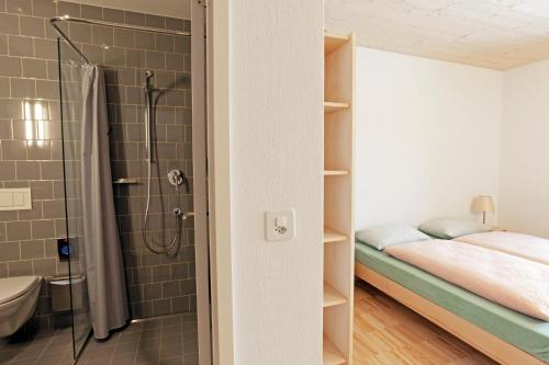 a small bathroom with a shower and a bed at St. Moritz Youth Hostel in St. Moritz