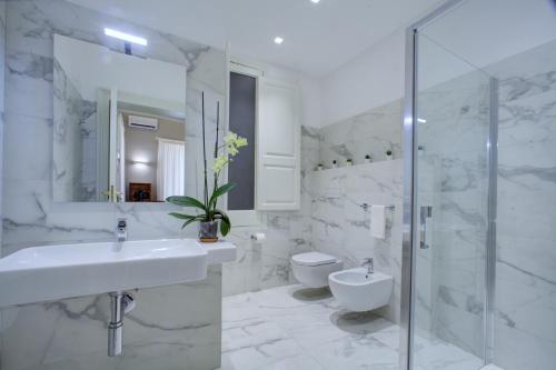 a white bathroom with a sink and a toilet at Palazzo Pastura B&B and Apartments in Catania