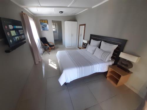 1 dormitorio con 1 cama grande con sábanas y almohadas blancas en The Private and Cosy Guest House 2 en Germiston