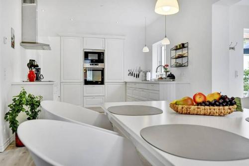 a white kitchen with a bowl of fruit on a counter at *****elegant feriebolig i hjertet af Kerteminde in Kerteminde