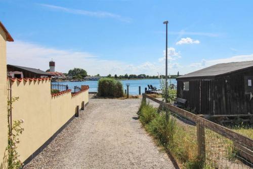 a dirt road next to a fence and a body of water at *****elegant feriebolig i hjertet af Kerteminde in Kerteminde