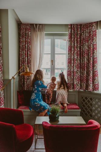two children sitting on a couch looking out a window at Hotel Goldener Ochs in Bad Ischl