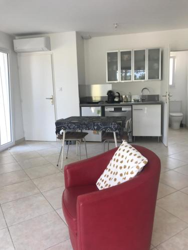 un salon avec un canapé rouge et une cuisine dans l'établissement studio neuf climatisé, à Les Fumades-Les Bains