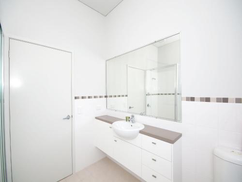 a white bathroom with a sink and a mirror at Stunning Holiday Townhouse in Tea Gardens