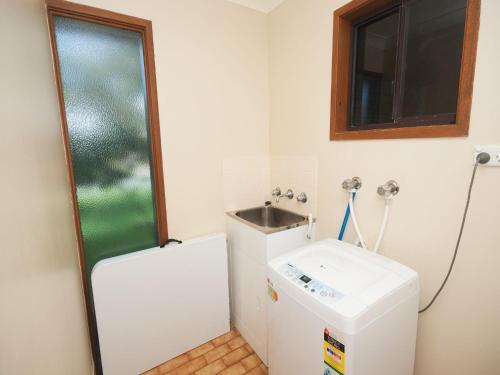 a small bathroom with a sink and a refrigerator at Pet Friendly on Pelican Close to Myall River in Hawks Nest