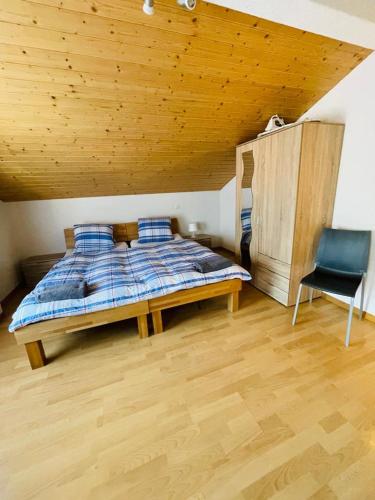 a bedroom with a bed with a wooden ceiling and a chair at Royal Swiss Apartments in Ringgenberg