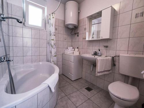 a bathroom with a tub and a toilet and a sink at Apartment Jaška in Rab