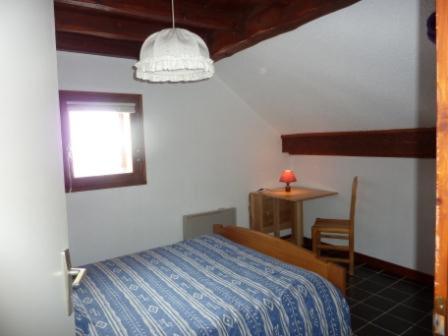 a bedroom with a bed and a table and a window at Magnimon 2 - Appartement rustique dans belle maison de village - Domaine Alpe d'Huez in Villard-Reculas