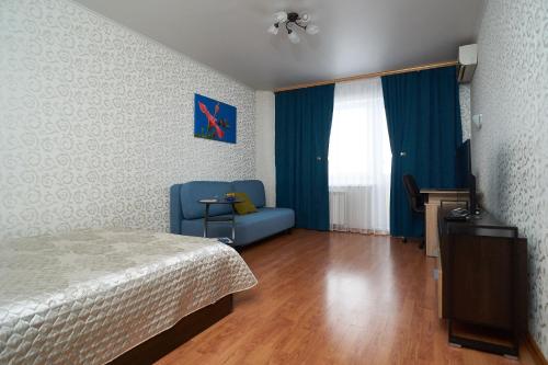 オムスクにあるУл.70 лет Октября 10のベッドルーム1室(ベッド1台、青い椅子付)