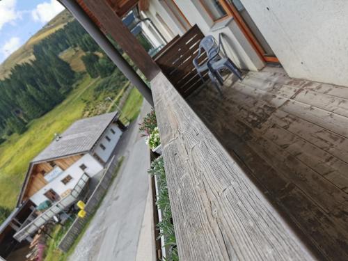 a wooden bench on a balcony with a view of a house at Alpengasthof Tanzstatt in Lachtal