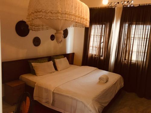 a bedroom with a bed with a chandelier above it at Judith Home FIKA CAFE in Kigali