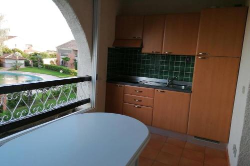 une cuisine avec une fenêtre offrant une vue sur la piscine dans l'établissement Appartement les pieds dans l'eau 300 m plage - 2 piscines, à Linguizzetta