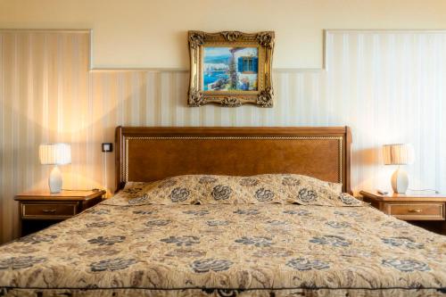 a bedroom with a bed and two nightstands with two lamps at Hotel Palace Marina Dinevi in Sveti Vlas
