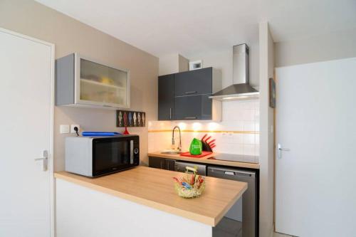 une cuisine avec un micro-ondes et un plan de travail dans l'établissement Cosylocation Les Hauts de Port Maria, à Quiberon