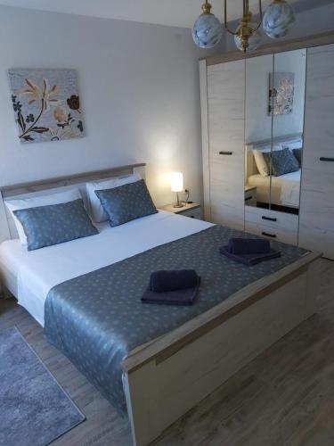 a bedroom with a large bed with blue pillows on it at Apartman Alma in Bihać